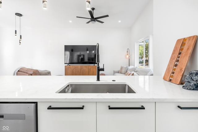 kitchen featuring sink, light stone countertops, white cabinets, and ceiling fan