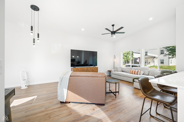 living room featuring ceiling fan, lofted ceiling, and light hardwood / wood-style flooring