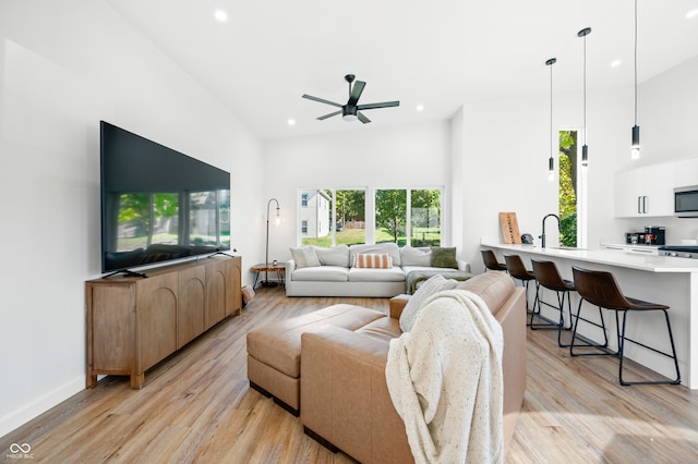 living room with light hardwood / wood-style flooring, high vaulted ceiling, and ceiling fan