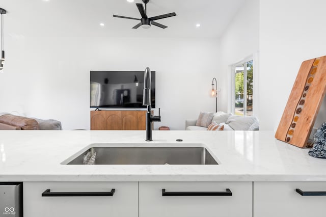 kitchen with white cabinetry, light stone countertops, sink, and ceiling fan