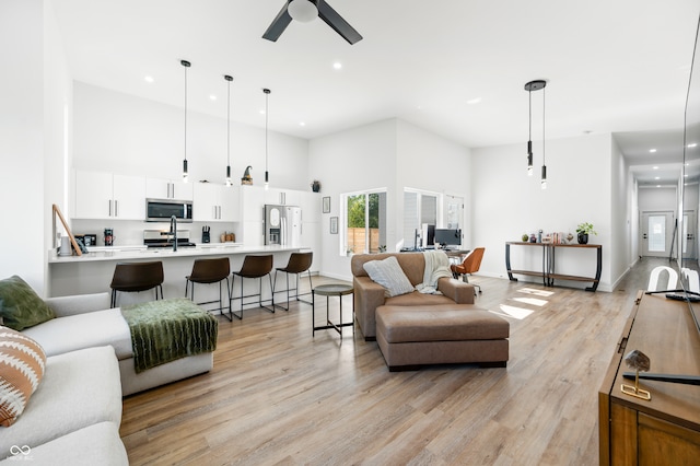 living room with sink, light hardwood / wood-style floors, a high ceiling, and ceiling fan