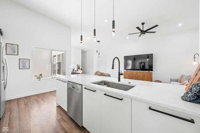 kitchen with stainless steel appliances, sink, light stone countertops, pendant lighting, and white cabinets