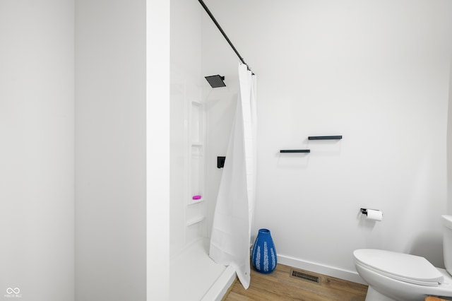 bathroom featuring toilet, curtained shower, and hardwood / wood-style flooring