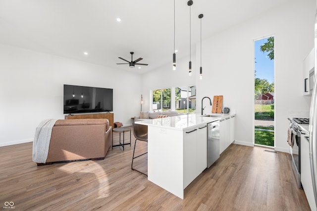 kitchen featuring kitchen peninsula, a breakfast bar area, white cabinetry, stainless steel appliances, and decorative light fixtures