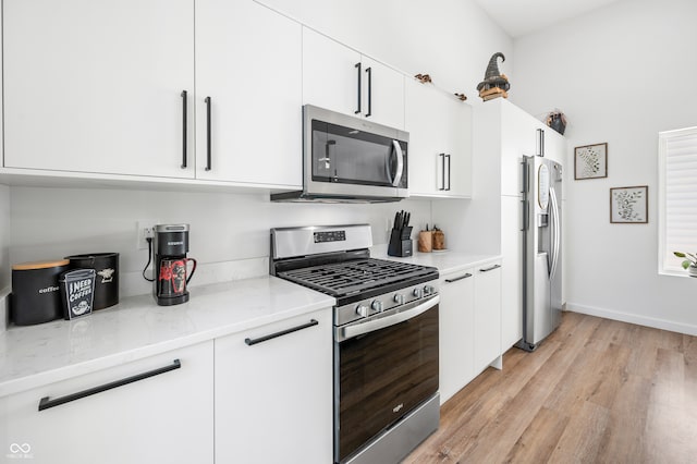 kitchen featuring white cabinetry, light hardwood / wood-style floors, appliances with stainless steel finishes, and light stone countertops