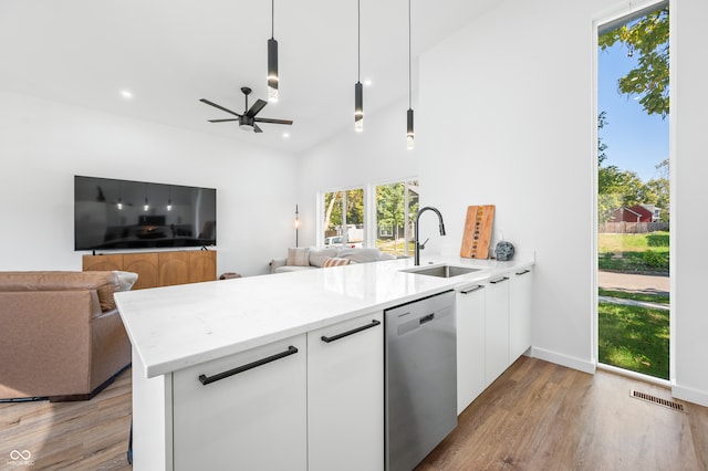 kitchen with sink, dishwasher, kitchen peninsula, pendant lighting, and white cabinets