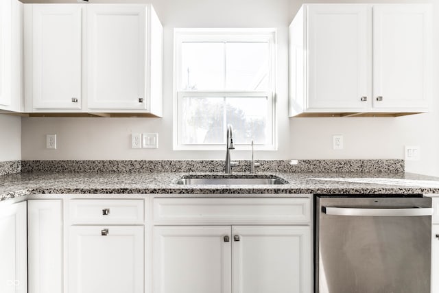 kitchen featuring sink, stainless steel dishwasher, white cabinets, and light stone counters