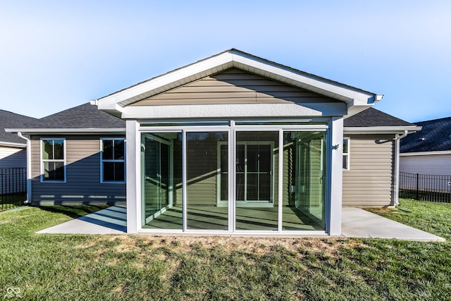 rear view of property with a lawn and a sunroom