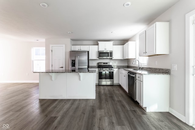 kitchen with white cabinetry, sink, dark stone countertops, a center island, and stainless steel appliances