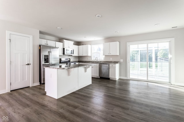 kitchen featuring a kitchen island, white cabinetry, appliances with stainless steel finishes, and dark stone countertops