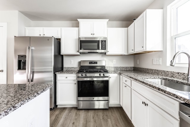 kitchen featuring white cabinetry, stainless steel appliances, stone countertops, and sink