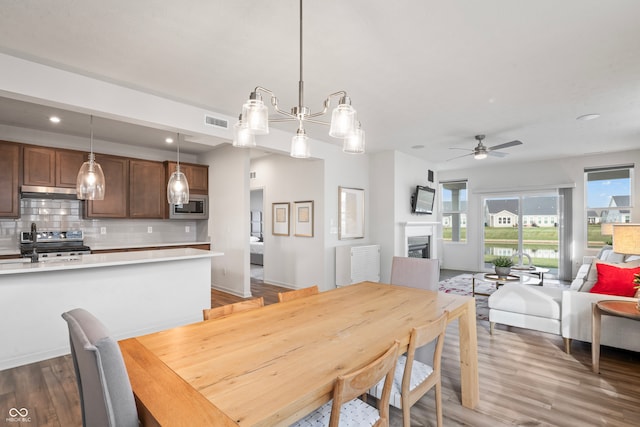 dining space with sink, ceiling fan with notable chandelier, and dark hardwood / wood-style flooring