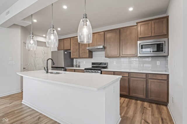 802 Weldon Way, Westfield, IN 46074 - kitchen with appliances with stainless steel finishes, under cabinet range hood, a center island with sink, wood finished floors, and decorative backsplash