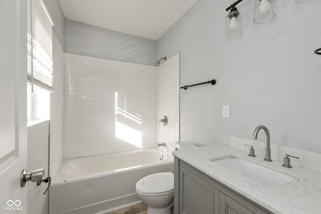 full bathroom featuring vanity, tiled shower / bath combo, and toilet