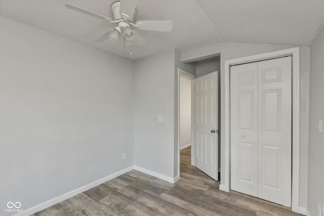 unfurnished bedroom with wood-type flooring, a closet, vaulted ceiling, and ceiling fan