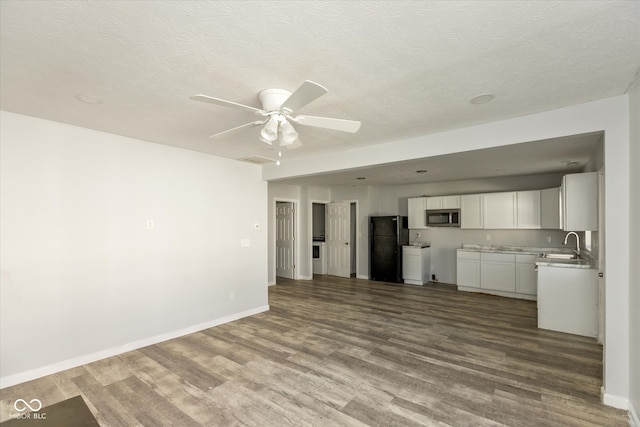 unfurnished living room featuring ceiling fan, sink, wood-type flooring, and a textured ceiling