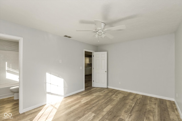 unfurnished bedroom with connected bathroom, hardwood / wood-style flooring, and ceiling fan