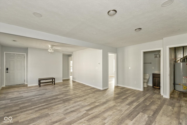 unfurnished living room featuring water heater, hardwood / wood-style floors, ceiling fan, and a textured ceiling