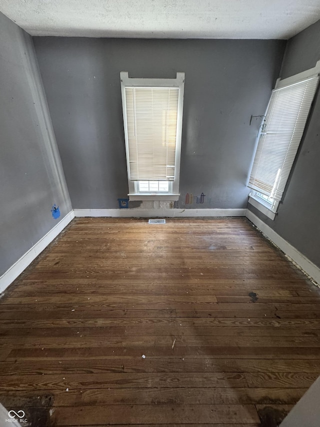 empty room with a textured ceiling and dark hardwood / wood-style floors