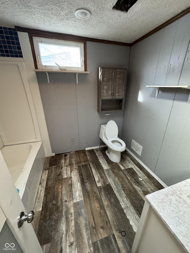 bathroom with wood walls, toilet, hardwood / wood-style flooring, and a tub