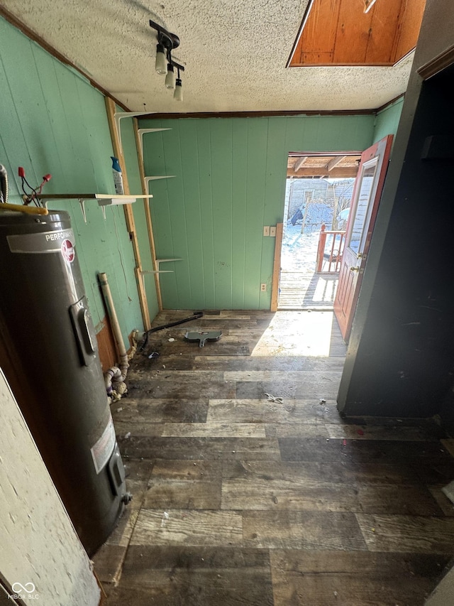 interior space featuring water heater, dark wood-type flooring, wood walls, and a textured ceiling