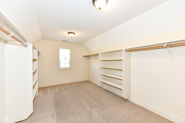 spacious closet featuring light colored carpet and lofted ceiling