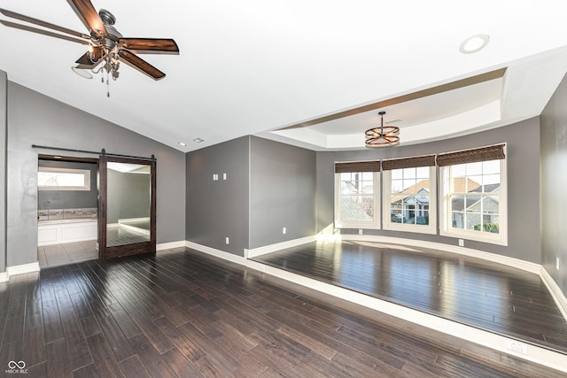 unfurnished room with dark hardwood / wood-style floors, a barn door, a raised ceiling, and ceiling fan