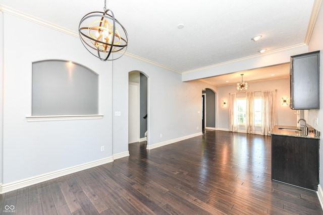 unfurnished living room featuring ornamental molding, an inviting chandelier, dark wood-type flooring, and sink