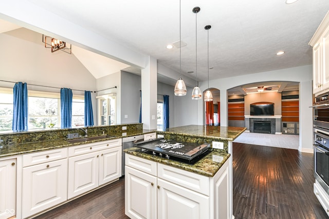 kitchen with dishwasher, sink, dark hardwood / wood-style floors, dark stone countertops, and a kitchen island