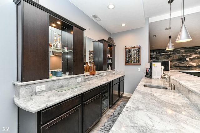 bar featuring hardwood / wood-style floors, backsplash, sink, hanging light fixtures, and light stone countertops