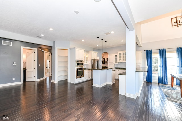 kitchen with dark hardwood / wood-style floors, a kitchen island, hanging light fixtures, and stainless steel appliances