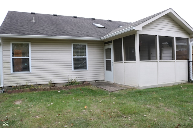 rear view of house with a yard and a sunroom