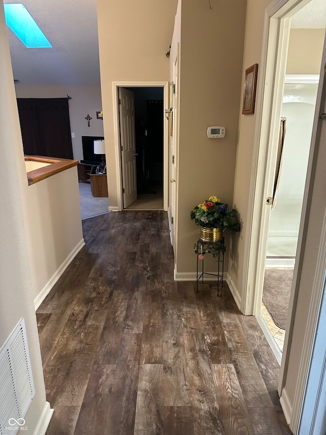 corridor featuring dark wood-type flooring and a skylight