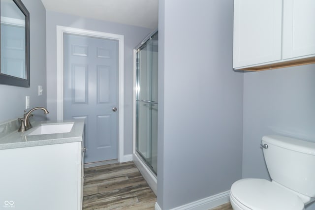 bathroom with toilet, an enclosed shower, hardwood / wood-style floors, and vanity