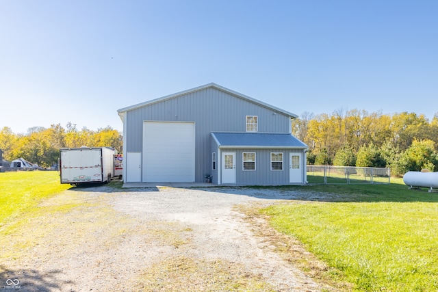 view of front of house with a front yard, a garage, and an outbuilding