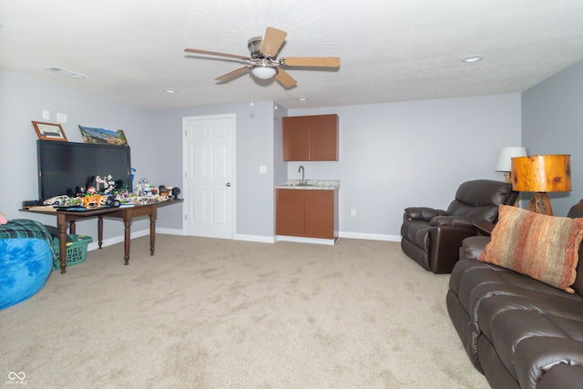 living room with sink, light colored carpet, and ceiling fan