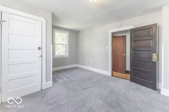 carpeted empty room featuring a textured ceiling