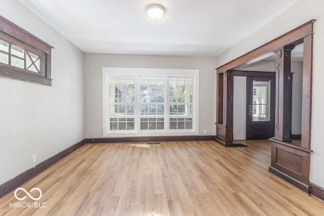 unfurnished living room featuring ornate columns and light hardwood / wood-style floors