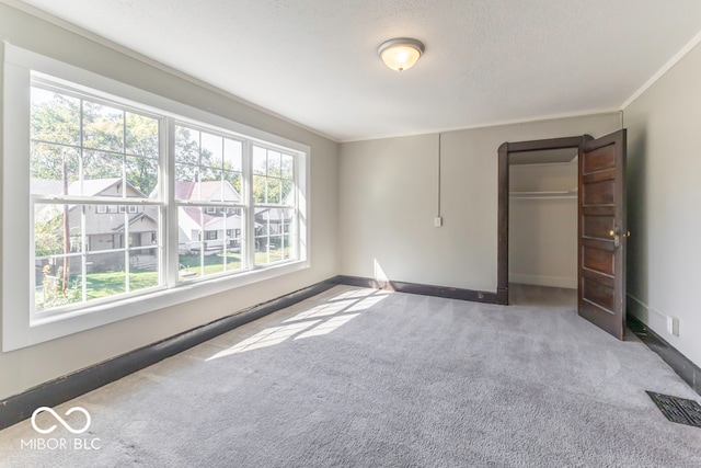 unfurnished bedroom featuring a closet, a textured ceiling, carpet flooring, and crown molding