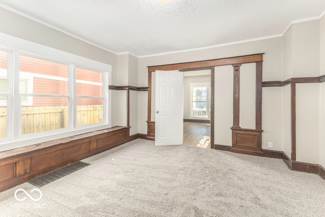 unfurnished bedroom featuring crown molding, a textured ceiling, carpet flooring, and decorative columns