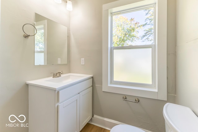 bathroom with a healthy amount of sunlight, vanity, hardwood / wood-style flooring, and toilet