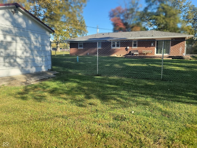 back of house featuring fence, brick siding, and a yard