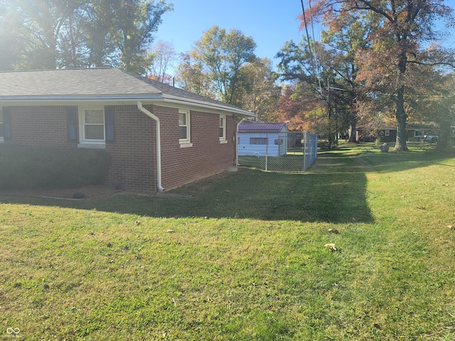 view of property exterior featuring brick siding, a yard, and fence