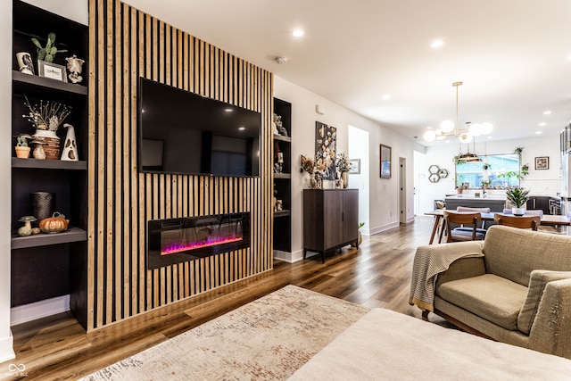 living room featuring a notable chandelier, hardwood / wood-style flooring, and built in features