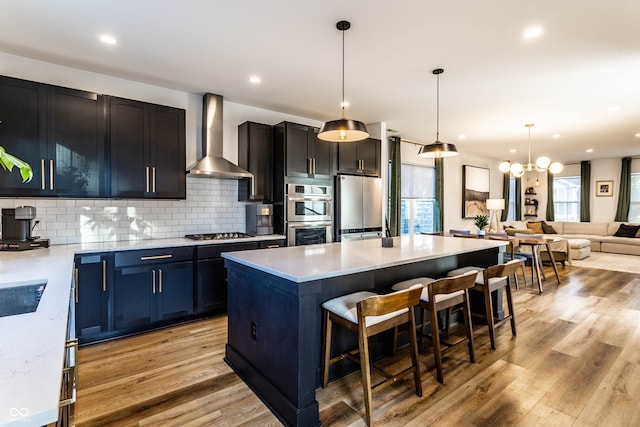 kitchen featuring light hardwood / wood-style flooring, wall chimney exhaust hood, stainless steel appliances, and a wealth of natural light