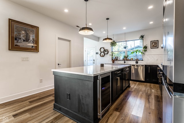 kitchen featuring a kitchen island, hanging light fixtures, stainless steel dishwasher, beverage cooler, and dark hardwood / wood-style floors