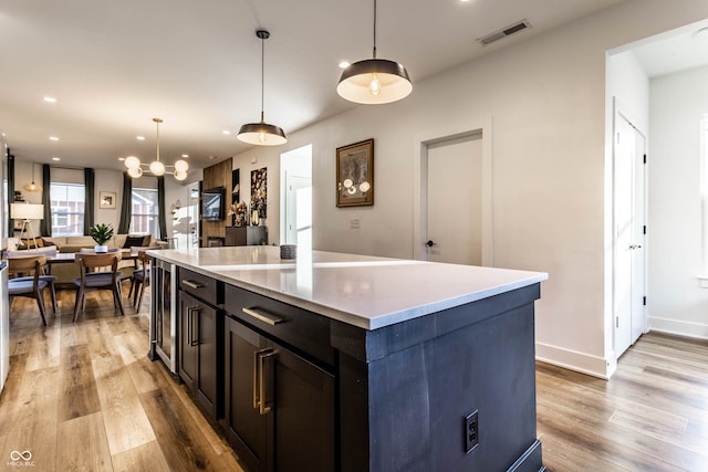 kitchen with an inviting chandelier, light hardwood / wood-style flooring, decorative light fixtures, and a kitchen island