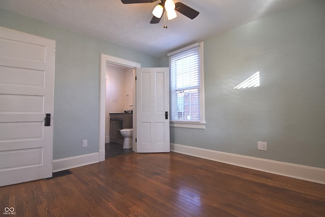 unfurnished bedroom featuring lofted ceiling, dark wood-type flooring, ceiling fan, a textured ceiling, and connected bathroom