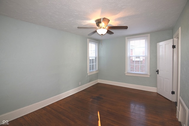 empty room featuring a textured ceiling, ceiling fan, and dark hardwood / wood-style floors