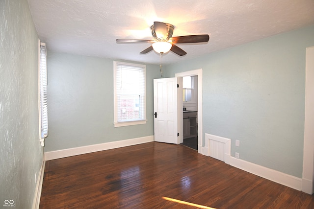 unfurnished bedroom with a textured ceiling, dark hardwood / wood-style flooring, ensuite bathroom, and ceiling fan